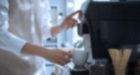 Stimmungsbild: eine Frau bedient einen Kaffeevollautomaten
