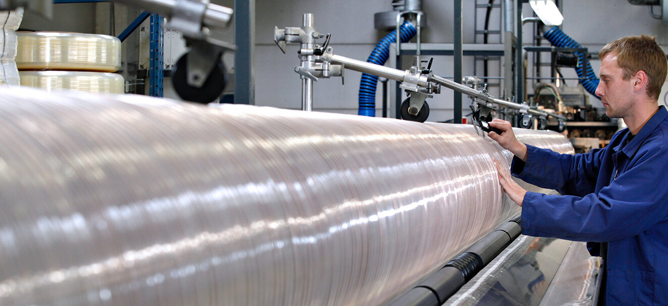 A Masterflex employee stands at a machine and monitors the production of a hose. 